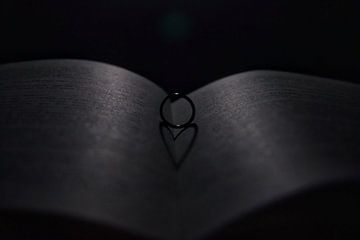 Photo of a ring on a book that forms a heart by Bram Jansen