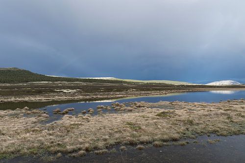 Norwegisch beleuchtete Berglandschaft mit Wasser und dunklem Himmel