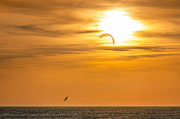 Windsurfer über dem Strand von Tarifa an der Südküste Spaniens bei Sonnenuntergang