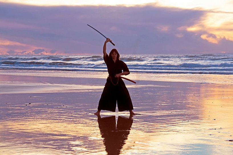 Young samurai woman with Japanese sword (katana) on the beach at sunset by Eye on You