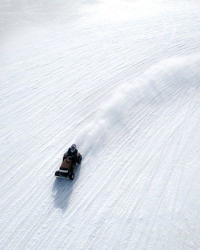 Une tondeuse autoportée roulant sur la glace dans un paysage hivernal minimaliste