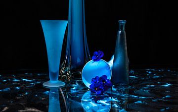 Compositie in blauw met glazen voorwerpen en een bloem. van Ineke Mighorst