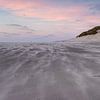 Stuifzand op het strand met een roze lucht van Paul Veen