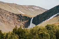 Large waterfall in the mountains of Norway, Scandinavia surrounded by trees and snow.
