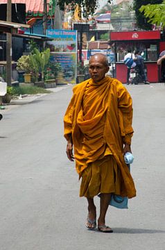 Monnik in gewaad loopt over straat in Thailand