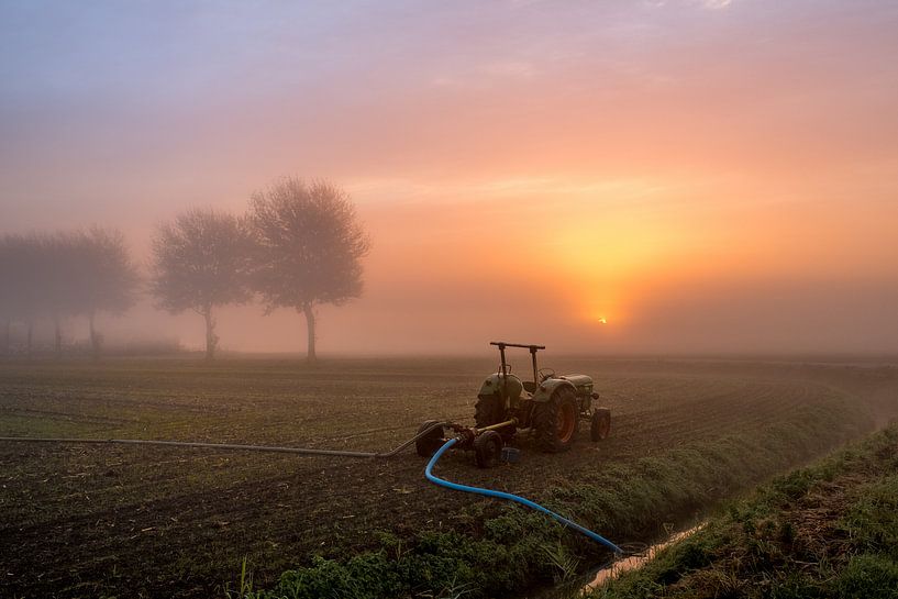 Tractor pompt water uit de sloot tijdens mistige zonsopkomst van Moetwil en van Dijk - Fotografie