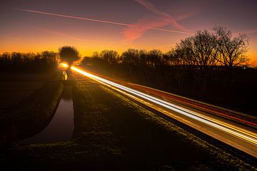 Mooie zonsondergang vergezeld met lichtsporen op de weg van Rob Baken