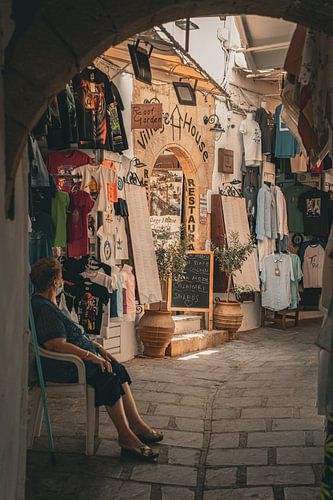 Old lady shaded for cool at a tourist shop