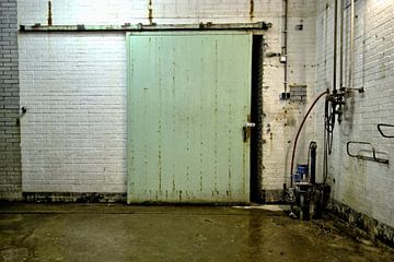 Foto van een groene deur in een verlaten melkfabriek. van Therese Brals