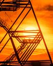 Die grafische Klarheit des Tetraeders im Kontrast zu den warmen Farben des Sonnenuntergangs erzeugt ein faszinierendes Zusammenspiel von Form, Licht und Silhouetten. Es ist ein Bild, das die Schönheit des Augenblicks und die beeindruckende Präsenz der Stahlkonstruktion vereint. von LICHTERKISTE Miniaturansicht