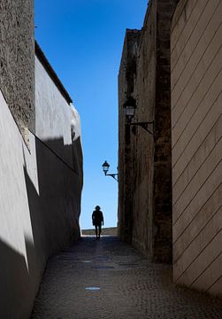 Wandelaar in smalle straat in Ibiza Stad Spanje van Albert Brunsting