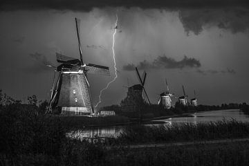 Blitze an den beleuchteten Windmühlen von Kinderdijk, Niederlande. Schwarz-Weiß-Foto.