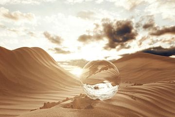 Glass ball on desert sand next to footprints by Besa Art
