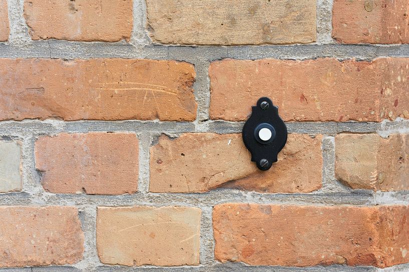 Doorbell button on a house wall by Heiko Kueverling