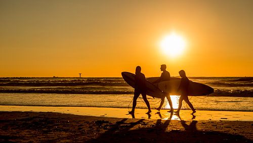 Surfers op het strand vlak voor zonsondergang van Dirk Jan Kralt