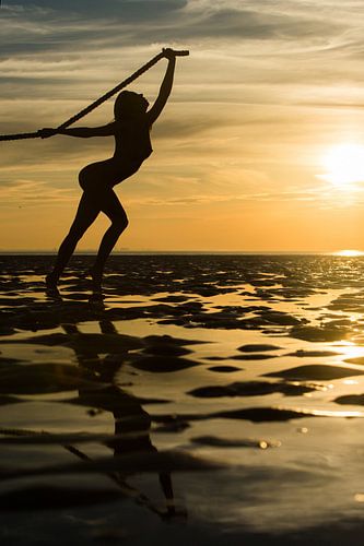 Artistic nude with a rope on the Wadden Sea at sunset