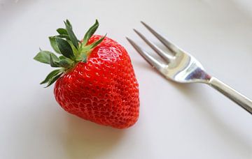 Fresh strawberry with green leaves on a white plate together with a small fork by MPfoto71