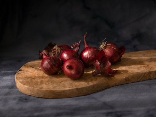 Nature morte d'oignons rouges sur une planche de bois avec un fond sombre