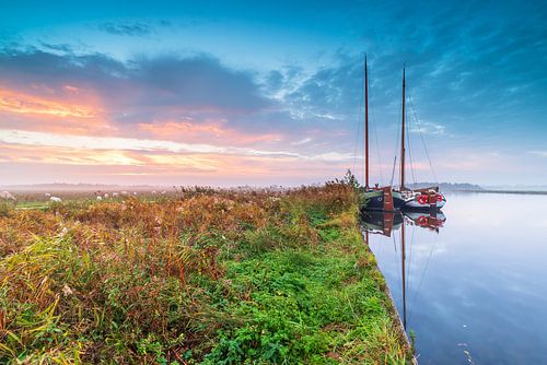 Bootjes langs de waterkant tijdens een fraaie zonsopkomst. van Taede Smedes