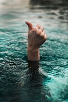 Hand steekt uit het water en steekt duim omhoog