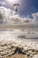 Kitesurfer auf tosendem Meer mit Kachellicht