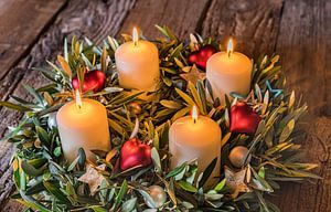 Festlicher Adventskranz mit vier brennenden Kerzen und Dekorationen von Alex Winter