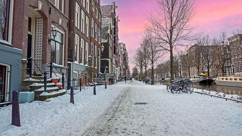 Besneeuwd Amsterdam in Nederland in de winter bij zonsondergang van Eye on You