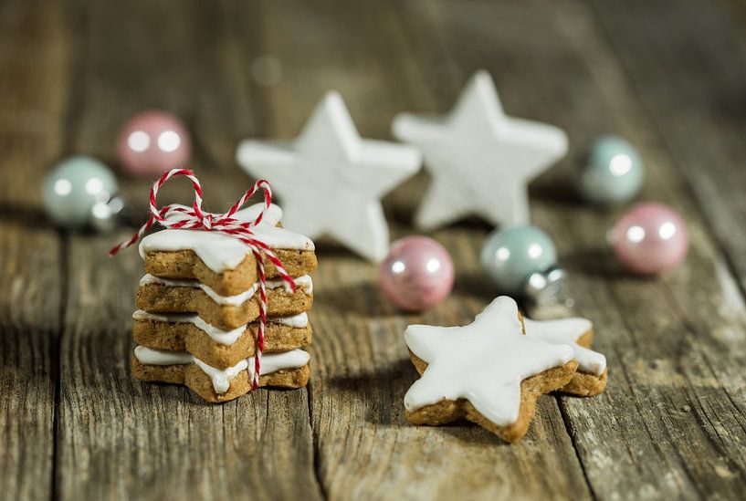 Compositon of christmas decorations with star shaped biscuits on wooden table by Alex Winter