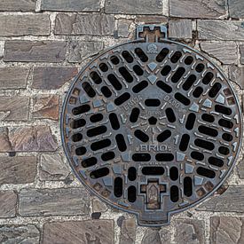 Gusseiserner Kanaldeckel in Pflastersteinen von MMFoto