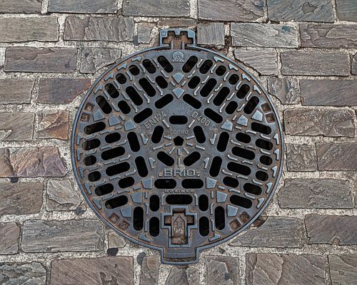 Cast iron manhole cover in cobblestones