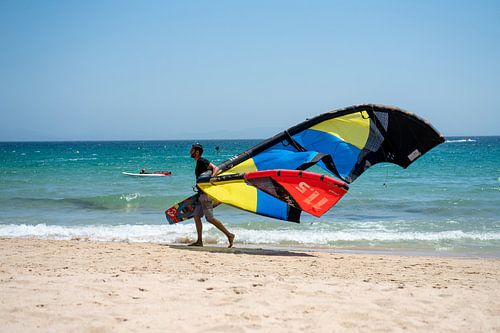 Surfer lopend langs de vloedlijn in Tarifa, Sanje.
