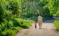 Man wandelt met kind op bospad van Ruud Morijn thumbnail