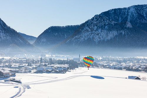 Heteluchtballonnen sieren de lucht boven een besneeuwd Inzell in Duitsland