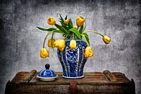 Delfts blauwe vaas met gele tulpen op oude kist