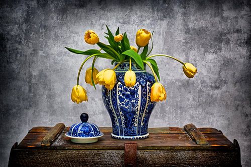 Delfts blauwe vaas met gele tulpen op oude kist