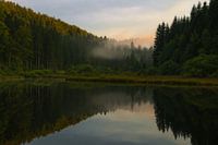 Zonsondergang en prachtige reflecties aan een meer in de Franse Jura.