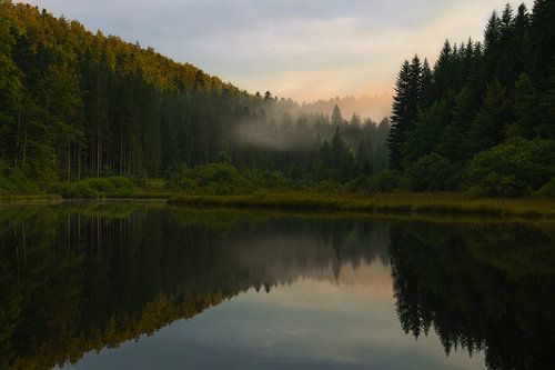 Zonsondergang en prachtige reflecties aan een meer in de Franse Jura.