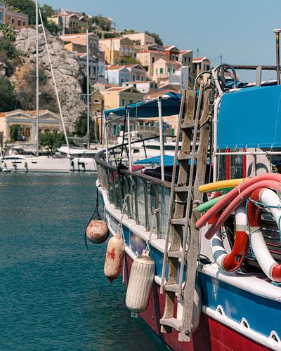 A boat with the beautiful houses of Symi island in the background.