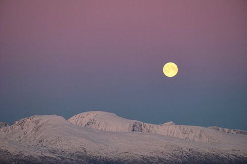 Volle maan boven besneeuwde bergen