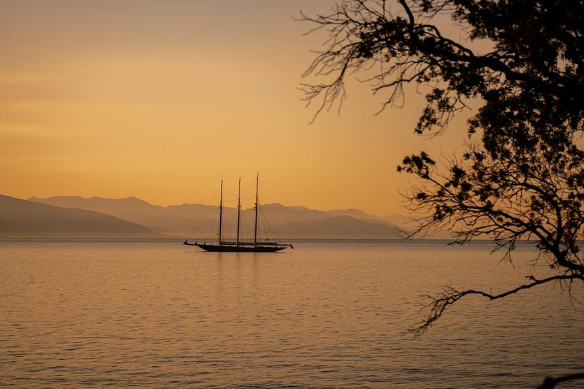 Een boot, zee en berglandschap bij dageraad van Leo Schindzielorz