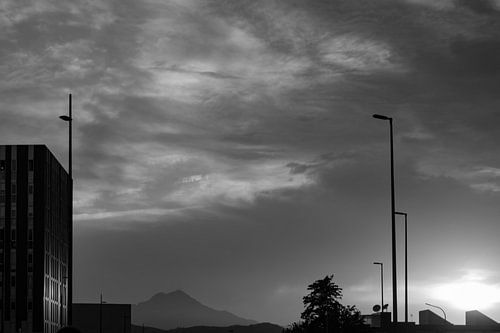 Black and white cityscape with mountain on the background during sunset
