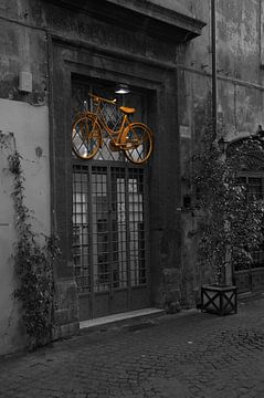 Gele fiets boven deur in Rome in Italië van Mike Bos