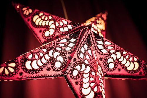 Verlichte kerstster met rode achtergrond