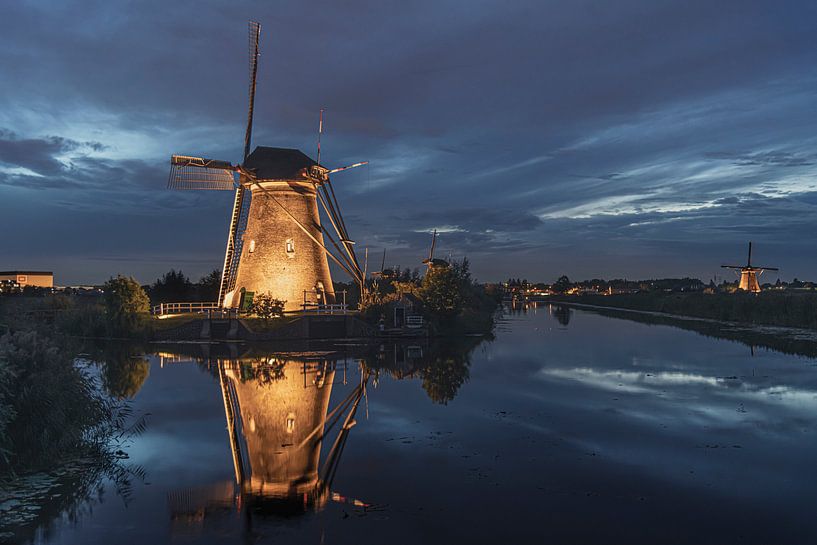 Illuminated windmill reflected on the calm canal water by Digikhmer