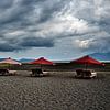 Vulkanisch strand en dramatische rode parasols van Frank Photos