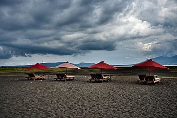 Vulkanisch strand en dramatische rode parasols
