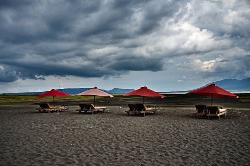 Vulkanisch strand en dramatische rode parasols van Frank Photos