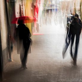 Twee mensen lopen van onder een overkapping de regen in van Jeroen Mank