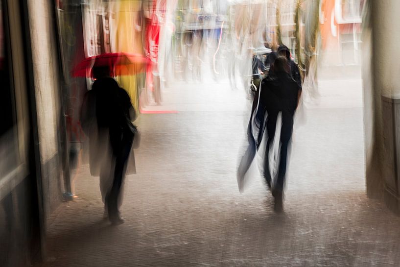 Twee mensen lopen van onder een overkapping de regen in van Jeroen Mank