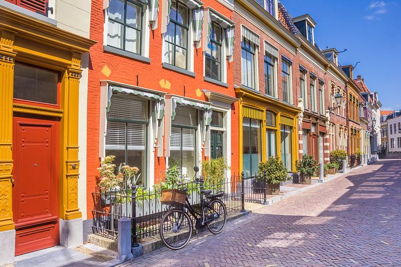 Un vélo se trouve devant des maisons colorées dans une rue de Leeuwarden. par Marc Venema